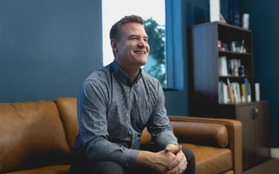 President of Urban Surfaces, Jeremy Britton, sitting on a couch in his office and smiling.