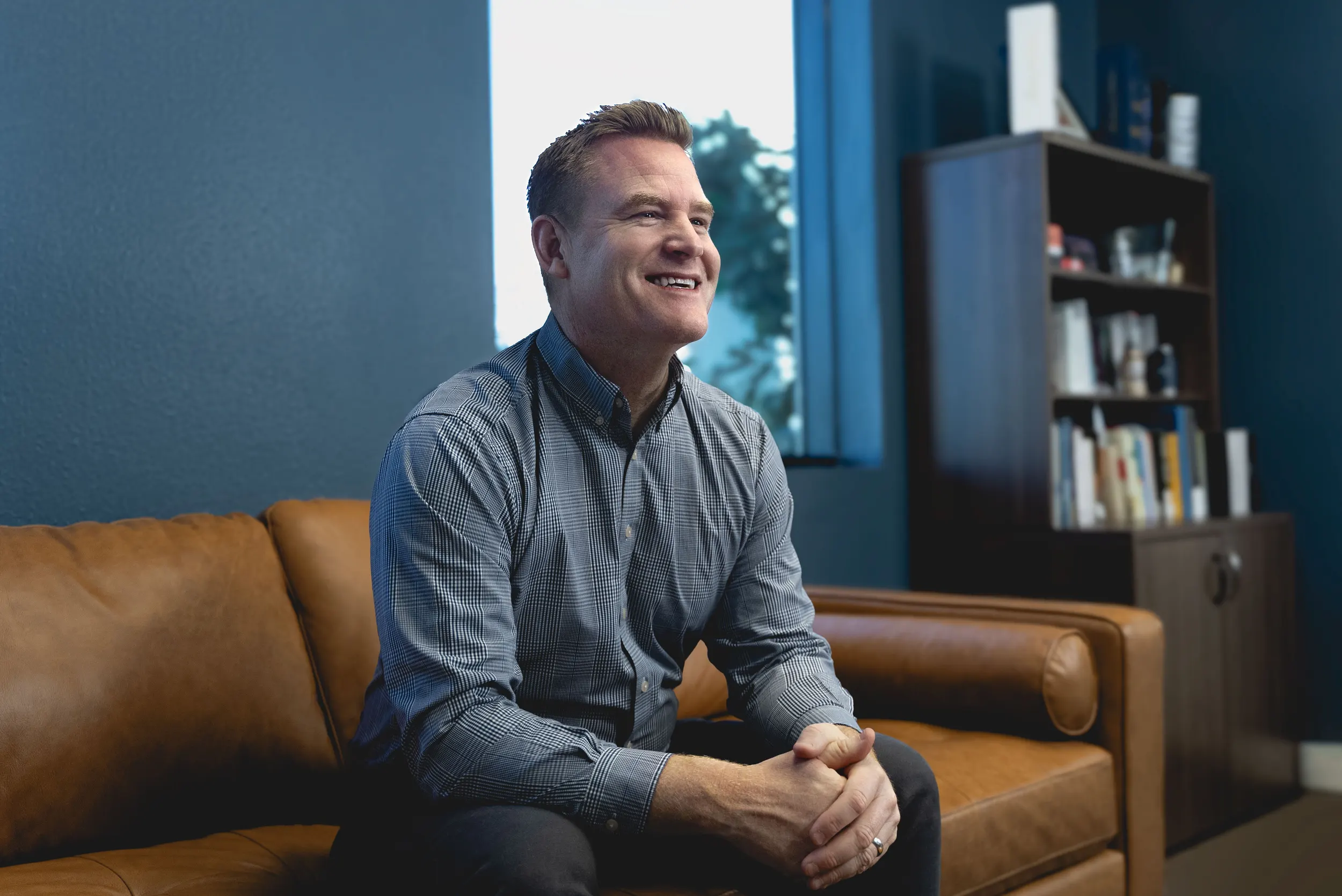 President of Urban Surfaces, Jeremy Britton, sitting on a couch in his office and smiling.